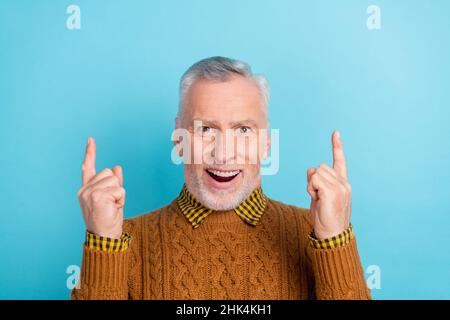 Foto von lustig beeindruckt pensionierten Mann tragen braunen Pullover zeigt nach oben leeren Raum isoliert blauen Hintergrund Stockfoto