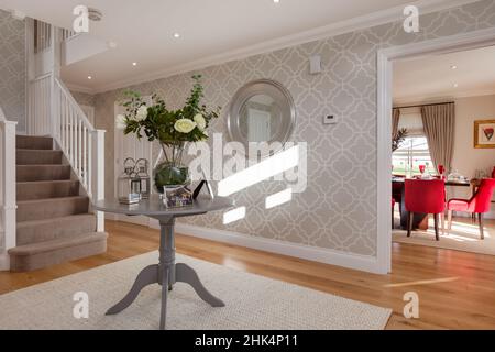 Alconbury Weald, Cambridgeshire - Oktober 17 2016: Moderne stilvolle Haus Empfangshalle mit Treppe zum ersten Stock, Tisch mit Blumen und Doo Stockfoto