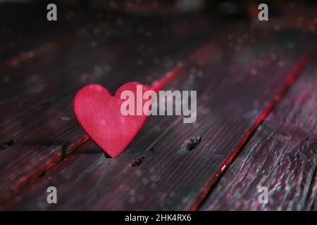 Rosafarbenes Herz auf dunklen rustikalen Holzplanken, auffälliges Liebeskonzept für Valentinstag, Muttertag, Vatertag oder Geburtstag, Kopierraum, ausgewählter Fokus, Narro Stockfoto