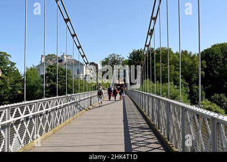 Chester, England - Juli 2021: Menschen gehen über die Queens Park Bridge, eine Hängebrücke über den Fluss Dee in der Nähe des Stadtzentrums. Stockfoto