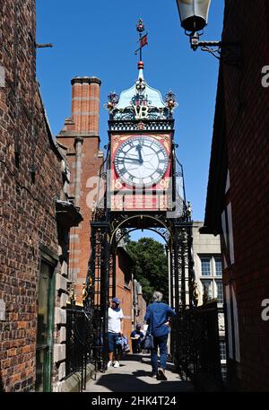 Chester, England - 2021. Juli: Besucher, die unter der Eastgate-Uhr an der Stadtmauer spazieren. Die Uhr steht an der Stelle des römischen Tores. Stockfoto