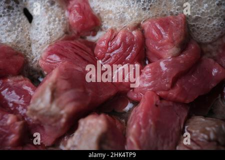 Rohe Fleischstücke, die für ein köstliches Abendessen in der Nähe zubereitet werden Stockfoto