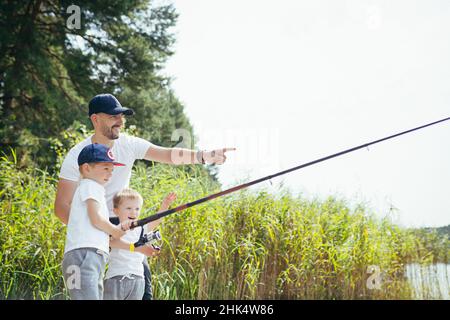 Ein Vater mit zwei jungen Söhnen fischt im Sommer am Wochenende am See Stockfoto