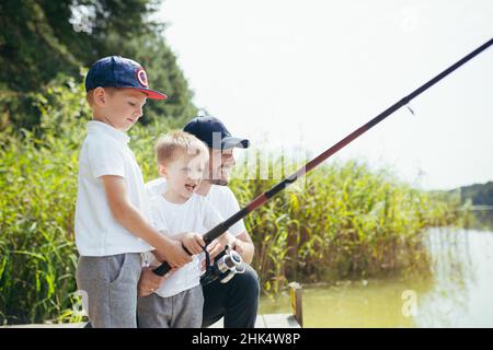 Ein Vater mit zwei jungen Söhnen fischt im Sommer am Wochenende am See Stockfoto