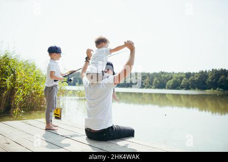 Ein Vater mit zwei jungen Söhnen fischt im Sommer am Wochenende am See Stockfoto