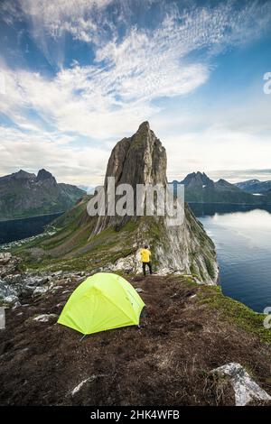 Wanderer mit Campingzelt, der den Berg Segla und den Fjord von Hesten bei Sonnenuntergang bewundert, Senja, Troms County, Norwegen, Skandinavien, Europa Stockfoto