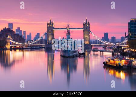 Blick bei Sonnenaufgang auf die HMS Belfast und die Tower Bridge in der Themse, mit Canary Wharf im Hintergrund, London, England, Großbritannien, Europa Stockfoto