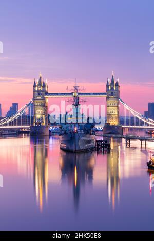 Blick bei Sonnenaufgang auf die HMS Belfast und die Tower Bridge in der Themse, mit Canary Wharf im Hintergrund, London, England, Großbritannien, Europa Stockfoto