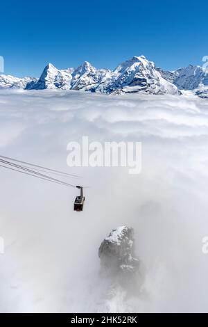 Klarer Himmel über den schneebedeckten Eiger-, Monch-, Jungfrau-Gipfeln mit Schilthorn-Seilbahn im dichten Nebel, Kanton Bern, Schweizer Alpen, Schweiz, Europa Stockfoto