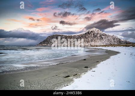 Wolken bei Sonnenuntergang über Berggipfel mit Schnee und eisigen Skagsanden Strand bedeckt, Flakstad, Lofoten Inseln, Norwegen, Skandinavien, Europa Stockfoto