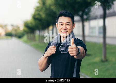 asian Mann nach Fitness-Training und Joggen glücklich Mann lächelt zeigt Daumen nach oben und schaut in die Kamera Stockfoto