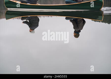 Spiegelung von zwei Männern in einem Boot. Lifestyle-Bild Kanu-Paddeln: Menschen spiegeln sich im klaren Wasser wider Stockfoto