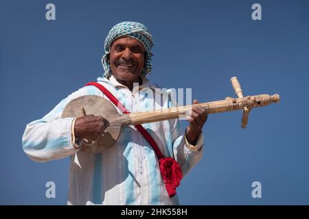 Marokkanischer Mann in traditioneller Kleidung, der ein traditionelles Gimbri-Instrument spielt, Ouarzazate, Atlasgebirge, Marokko, Nordafrika, Afrika Stockfoto