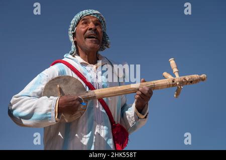 Marokkanischer Mann in traditioneller Kleidung, der ein traditionelles Gimbri-Instrument spielt, Ouarzazate, Atlasgebirge, Marokko, Nordafrika, Afrika Stockfoto