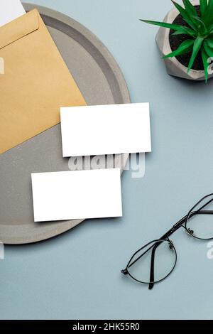 Zwei Visitenkarten-Mockups auf einem modernen Minimal-Arbeitsplatz mit Brille. Desktop-Ansicht von oben. Stockfoto