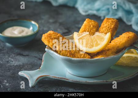 Fischfinger mit Zitrone und Sauerrahm auf blauem Hintergrund Stockfoto