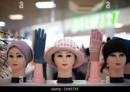 Im Geschäft gibt es Schaufensterpuppen Köpfe in gestrickten Hüten und Handschuhen. Abteilung für den Verkauf von Hüten. Stockfoto