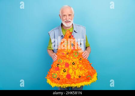 Foto von ziemlich gut aussehend Mann Rentner gekleidet Retro Denim Weste lächelnd halten Pizza Pinata isoliert blauen Hintergrund Stockfoto