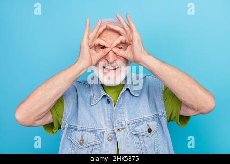 Foto von aufgeregt lustig Rentner tragen Vintage Jeans Weste zeigt Finger Brille lächelnd isoliert blauen Hintergrund Stockfoto