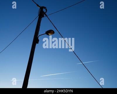 Eine Vision von abstrakter Schönheit und Kontrasten - Straßenlicht, Drähte und Dampfspuren bei Sonnenaufgang, von einem Fußweg in Radley Village aus gesehen. Mein frühes Joggen Stockfoto