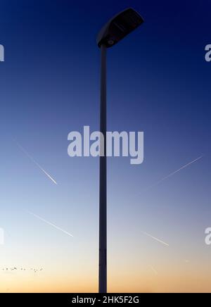 Eine Vision von abstrakter Schönheit und Kontrasten - Straßenlicht und ein Muster von Dampfwegen bei Sonnenaufgang, von einem Fußweg in Radley Village aus gesehen. Plus ein Pas Stockfoto