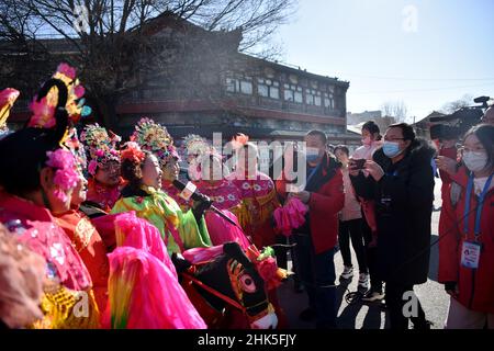 ZHANGJIAKOU, CHINA - 2. FEBRUAR 2022 - Journalisten von nicht registrierten Medien für die Olympischen Winterspiele 2022 in Peking interviewen Menschen, die Volksmusik spielen Stockfoto