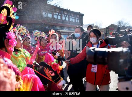 ZHANGJIAKOU, CHINA - 2. FEBRUAR 2022 - Journalisten von nicht registrierten Medien für die Olympischen Winterspiele 2022 in Peking interviewen Menschen, die Volksmusik spielen Stockfoto