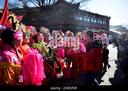 ZHANGJIAKOU, CHINA - 2. FEBRUAR 2022 - Journalisten von nicht registrierten Medien für die Olympischen Winterspiele 2022 in Peking interviewen Menschen, die Volksmusik spielen Stockfoto