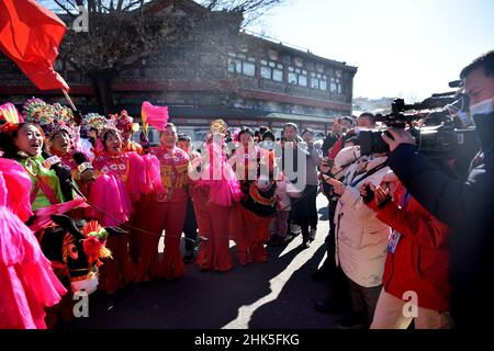 ZHANGJIAKOU, CHINA - 2. FEBRUAR 2022 - Journalisten von nicht registrierten Medien für die Olympischen Winterspiele 2022 in Peking interviewen Menschen, die Volksmusik spielen Stockfoto