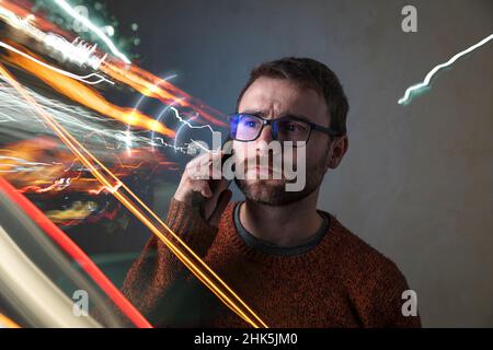 Ein Mann im Metaverse, umgeben von Lichtern und futuristischen Effekten, telefoniert zwischen unendlichen Wellen der Raumzeit Stockfoto