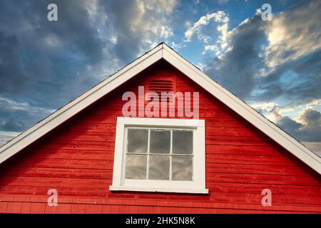 Gipfel eines rustikalen roten Gebäudes vor stürmischem Himmel. Stockfoto