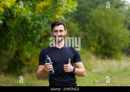 Müde erschöpft dehydriert Athlete Mann Läufer Trinkwasser Flasche nach dem Training. Sportflasche Getränk. Männlicher Sportler. Läufer verschwitzt und durstig afte Stockfoto