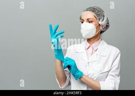 Porträt einer unglücklichen jungen Ärztin in einer medizinischen Maske auf grauem Hintergrund. Die müden Augen des Arztes. Das Konzept des Coronavirus. Stockfoto