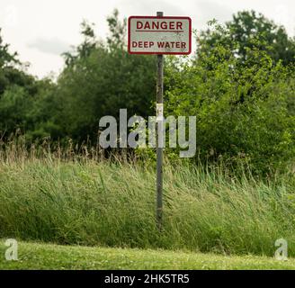 Gefahr Tiefwasser Pfahl montiert Schild neben dem See Stockfoto