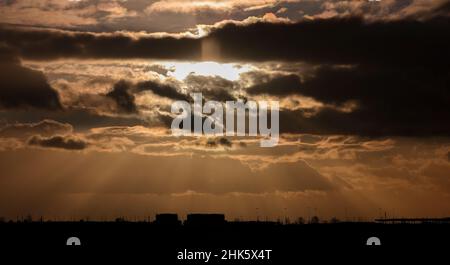 Leipzig, Deutschland. 02nd. Februar 2022. Bei wechselhaftem und windigem Wetter untergeht die Sonne am Flughafen Leipzig/Halle hinter den Wolken. Quelle: Jan Woitas/dpa-Zentralbild/dpa/Alamy Live News Stockfoto