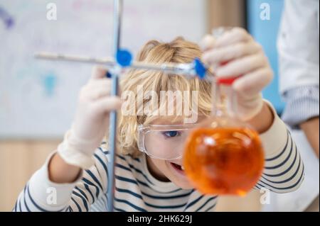 Nahaufnahme eines Jungen, der den Kolben mit Flüssigkeit untersucht Stockfoto