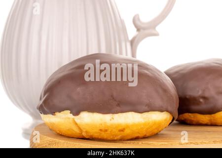 Zwei aromatisierte Schokoladendonuts auf einem Holztablett mit einem Milchkännchen aus Keramik, Makro, isoliert auf weißem Hintergrund. Stockfoto