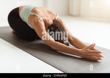 Nahaufnahme der jungen Frau, die in der Kinderpose meditiert und Yoga praktiziert Stockfoto