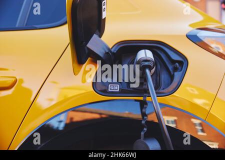 Elektroauto vor dem Haus auf der Straße eingesteckt Stockfoto