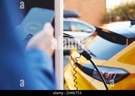 Elektroauto mit Smartphone-App auf der Straße angeschlossen Stockfoto