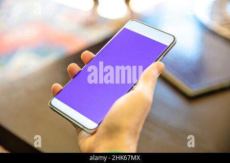 Leerer Bildschirm Smartphone auf einer männlichen rechten Hand, Nahaufnahme. Mann halten Handy mit leerem Display, verwischen inneren Hintergrund zu Hause. Platz kopieren, Vorlage Stockfoto