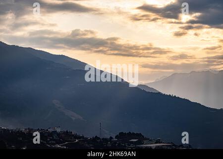 Der orangefarbene Sonnenuntergang über dem Berghorizont in der Dämmerung aus einem flachen Winkel wurde am tawang arunachal pradesh india aufgenommen. Stockfoto