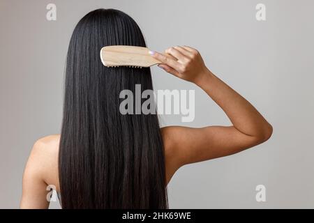 Brünette junge Frau Bürsten Haare im Studio Stockfoto