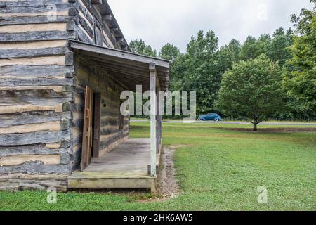 Teilansicht einer alten rustikalen Kabine mit einem Oldtimer aus dem Jahr 1940s, der im Hintergrund an einem bewölkten Tag im Spätsommer durch die Wälder fährt Stockfoto