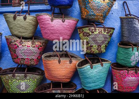 Viele bunte Korbkörbe, die auf einem marokkanischen Markt an einer blauen Wand verteilt werden Stockfoto