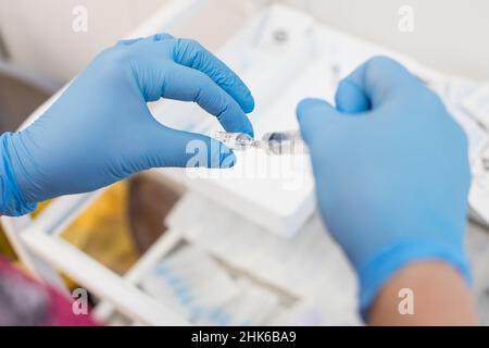 Arzt mit Spritze bereitet sich auf eine Injektion vor. Arzthände mit Spritze, Fläschchen. Flüssiges Medikament oder Impfstoff für die Behandlung, Grippe in der Hand des Stockfoto