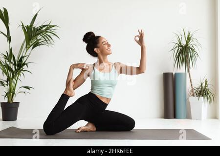 Yoga-Practive. Schöne junge Brünette Frau macht Meerjungfrau Pose im Studio Stockfoto