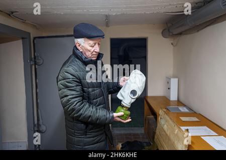 USCHHOROD, UKRAINE - 2. FEBRUAR 2022 - der Katastrophenschutzexperte Anatolii Koboziev demonstriert eine Gasmaske im Bombenschutz des Uschhorod Vodok Stockfoto