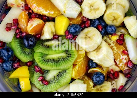 Nahaufnahme farbenfroher Obstsalat in einer Schüssel mit vielen verschiedenen Obstsorten wie Kiwi-Banane und Heidelbeeren Stockfoto