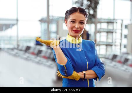 Fröhlicher Flugbegleiter, der im Flughafenterminal steht Stockfoto